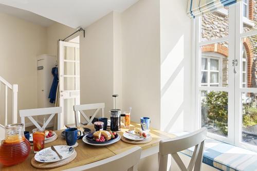 a dining room table with plates of food on it at Old Mill Court, Charming Mews House with Parking in Brixham
