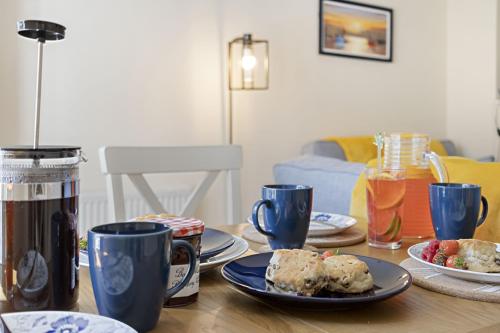 a table with plates of food and cups on it at Old Mill Court, Charming Mews House with Parking in Brixham