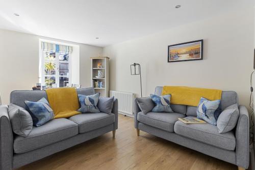 a living room with two gray couches and a window at Old Mill Court, Charming Mews House with Parking in Brixham