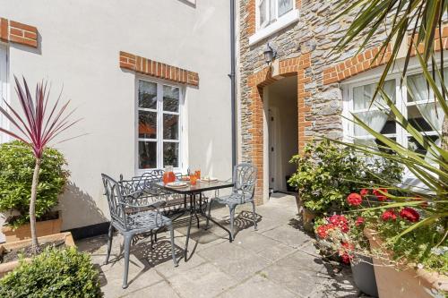 a patio with a table and chairs and plants at Old Mill Court, Charming Mews House with Parking in Brixham