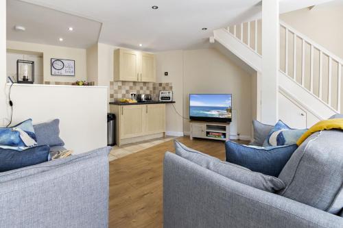 a living room with two blue couches and a kitchen at Old Mill Court, Charming Mews House with Parking in Brixham