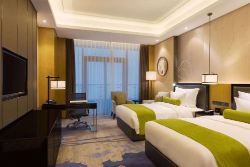 a hotel room with two beds and a desk and a television at Wyndham Chongqing Yuelai in Chongqing