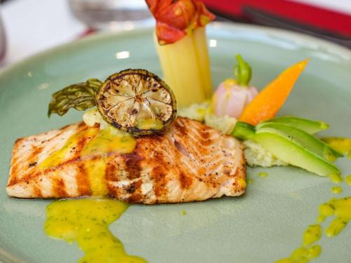a plate of food with a piece of fish and vegetables at Ibis Sfax in Sfax