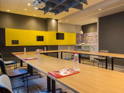 a conference room with tables and chairs and yellow walls at Ibis Sfax in Sfax
