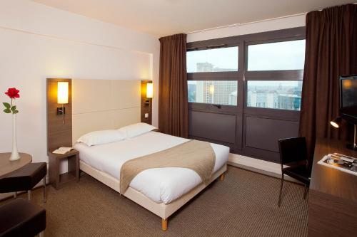 pokój hotelowy z łóżkiem i dużym oknem w obiekcie Séjours & Affaires Lille Europe w Lille