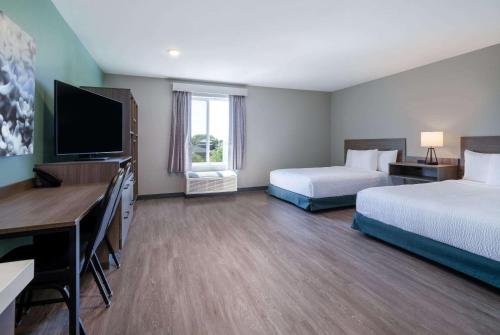 a hotel room with two beds and a flat screen tv at ECHO Suites Extended Stay by Wyndham Nashville/ Gallatin in Gallatin