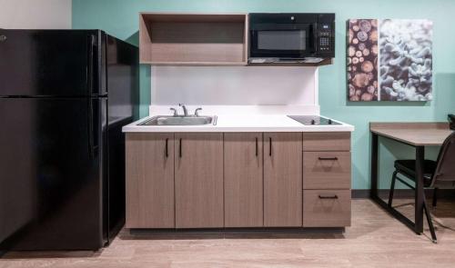 a kitchen with a sink and a black refrigerator at ECHO Suites Extended Stay by Wyndham Nashville/ Gallatin in Gallatin