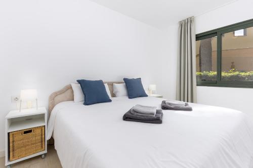 a white bedroom with a large bed and a window at Home2Book Poolside & Terrace Retreat, Corralejo in La Oliva