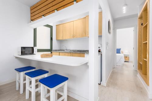 a kitchen with two blue stools and a counter at Home2Book Poolside & Terrace Retreat, Corralejo in La Oliva