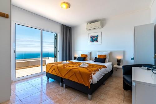 a bedroom with a bed with a view of the ocean at Casa Flora, 2 quartos,vista mar in Arco da Calheta