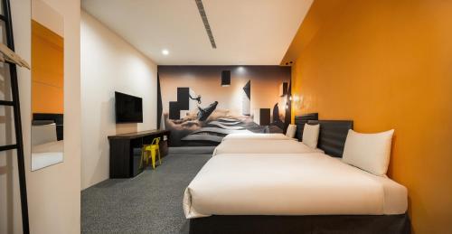 a row of beds in a room with orange walls at 凝萃文旅 台中車站店 NCH-Business Hotel in Taichung