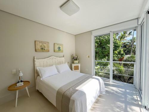a bedroom with a bed and a large window at Casa Bella - Deslumbrante c/Enxoval - Riviera Md 5 in Riviera de São Lourenço
