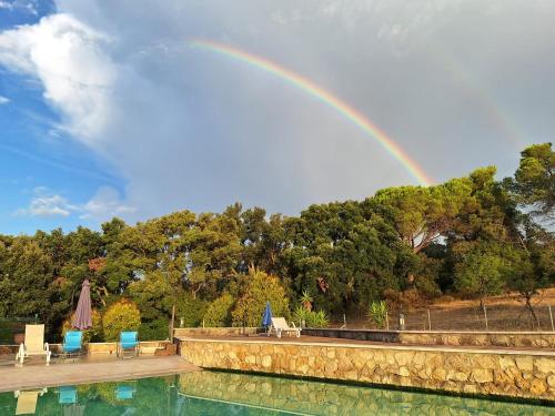 a rainbow over a pool with chairs and a table at Agriturismo Piccolo Paradiso in Riparbella