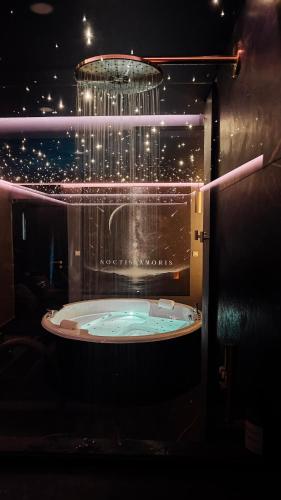 a bath tub in a room with a chandelier at Noctis Amoris Suite Atypique Maizeret in Samson