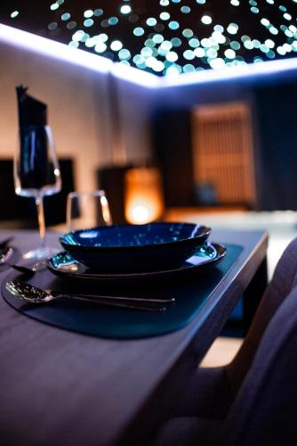 a table with a blue plate and a glass of wine at Noctis Amoris Suite Atypique Maizeret in Samson