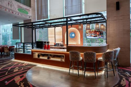 a bar in a restaurant with stools at Novotel Ahmedabad in Ahmedabad