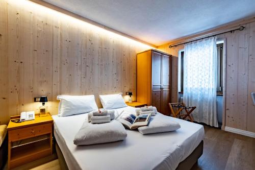 a bedroom with a large white bed with two pillows at Hotel Grizzly "Ski-in Ski-out" in Folgaria