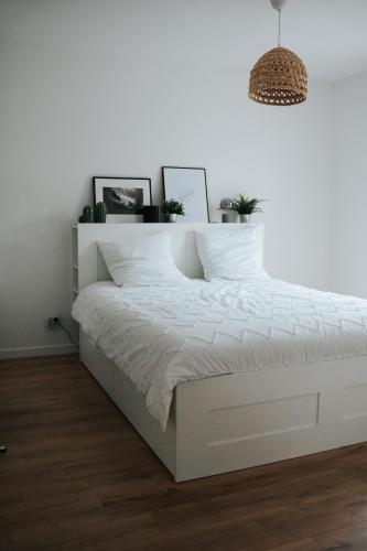 - un lit blanc dans une chambre blanche avec un cadre de lit blanc dans l'établissement Résidence Boho Lacanau, à Lacanau