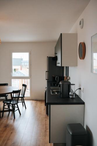 une cuisine avec un comptoir et une table avec des chaises dans l'établissement Résidence Boho Lacanau, à Lacanau