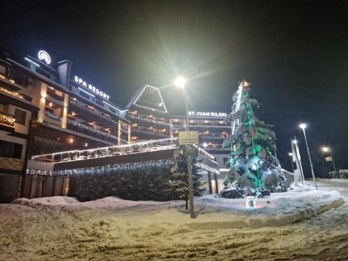 un arbre de Noël recouvert de neige devant un bâtiment dans l'établissement Family Luxury Private Apartment for 4 max 6 people in 4 star SPA Resort St Ivan Rilski, Bansko, à Bansko