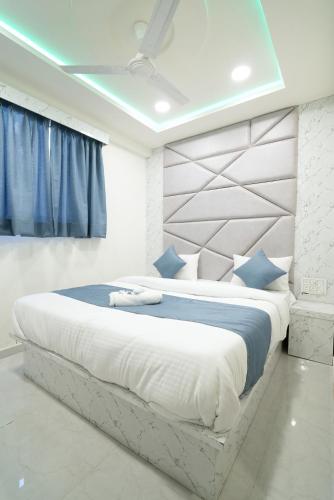 a bedroom with a large white bed with blue pillows at Hotel Nest Sky in Ahmedabad