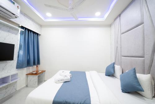 a bedroom with a bed with blue pillows and a tv at Hotel Nest Sky in Ahmedabad