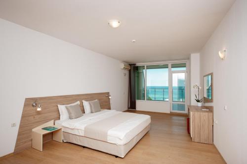 a bedroom with a white bed and a large window at Silver Beach Apart Complex in Byala
