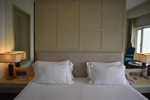 a hotel room with a bed with two white pillows at Chanakya Hotel, Patna in Patna