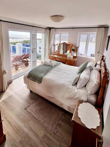 a bedroom with a large bed and a balcony at Baywatch Paternoster - The Penthouse in Paternoster