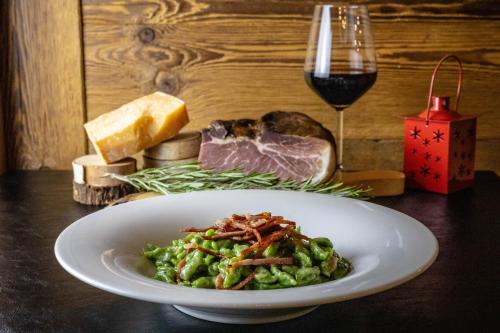a plate of food on a table with a glass of wine at Hotel Grizzly "Ski-in Ski-out" in Folgaria