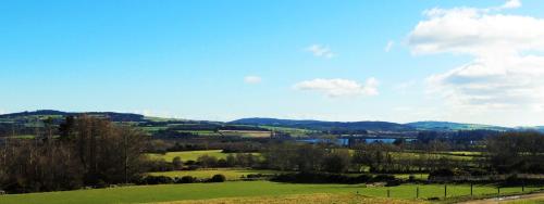 a green field with a lake and mountains in the background at Lus Mor in Roundwood