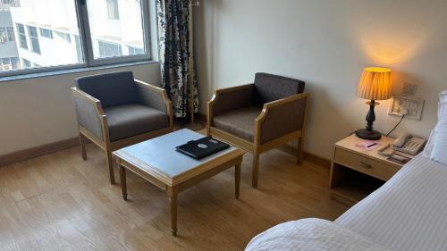 a room with two chairs and a table and a bed at Chanakya Hotel, Patna in Patna