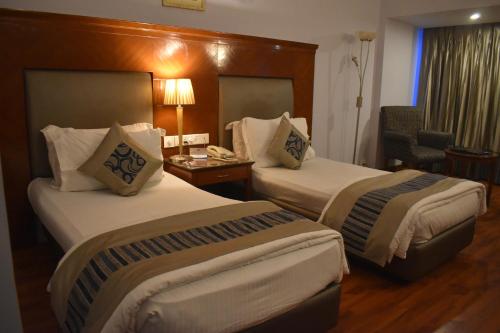 a hotel room with two beds and a desk at Chanakya Hotel, Patna in Patna