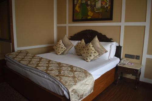 a bedroom with a bed with pillows on it at Chanakya Hotel, Patna in Patna