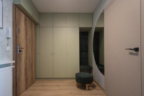 a hallway with a green stool and white cabinets at Apartamenty Cicha - bezpłatny parking in Krynica Zdrój