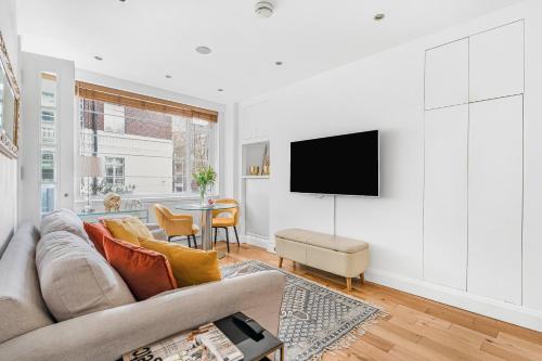 a living room with a couch and a tv on a wall at Elegant 1 Bedroom flat near Harrods in London