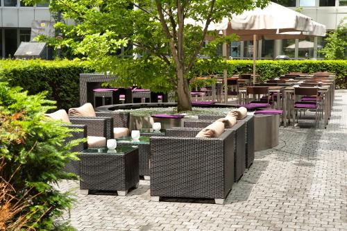 a patio with chairs and tables and a tree at INNSiDE by Meliá München Parkstadt Schwabing in Munich