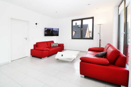 a living room with two red chairs and a table at Ferienwohnung Leuchtfeuer 6 OG in Peenemünde