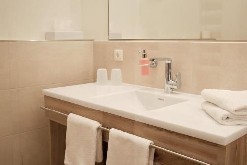 a bathroom with a sink and a mirror and towels at Landgasthof Hotel Rittmayer in Hallerndorf