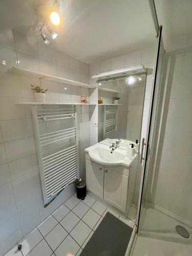 une salle de bain blanche avec un lavabo et une douche dans l'établissement BnGo I Maison Terracotta I Jardin, Garage, 3 chambres, 9 personnes, à Villeurbanne