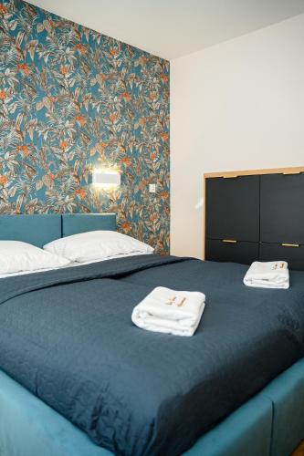 a bedroom with a blue bed with towels on it at Apartamenty Cicha - bezpłatny parking in Krynica Zdrój
