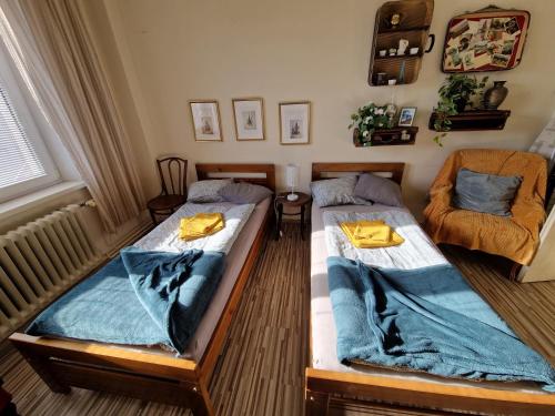 2 camas individuales en una habitación con silla en Touch of history apartment, en Bratislava
