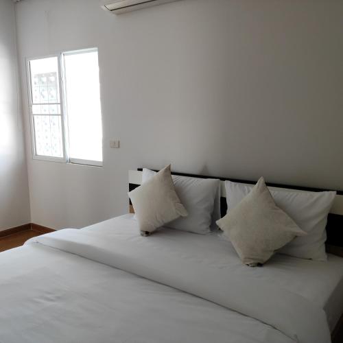 a white bed with white pillows and a window at The first house 11126 in Ban Phlu Yai