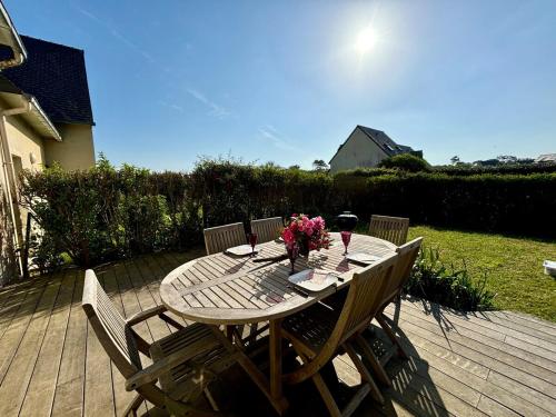 a wooden table with flowers and wine glasses on a deck at Le Cocon Iodé - 100m des plages-GR34-skatepark-kite-surf-voile-terrasse-jardin in Clohars-Carnoët