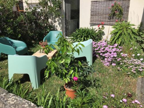 a garden with two blue chairs and flowers at Le Cocon Iodé - 100m des plages-GR34-skatepark-kite-surf-voile-terrasse-jardin in Clohars-Carnoët