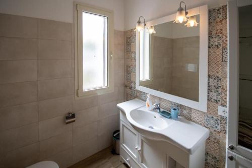 een badkamer met een witte wastafel en een spiegel bij Casa Marisol in Orosei