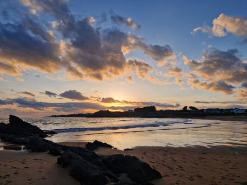 a sunset on a beach with rocks in the sand at Le Cocon Iodé - 100m des plages-GR34-skatepark-kite-surf-voile-terrasse-jardin in Clohars-Carnoët