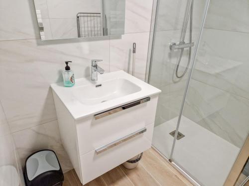 une salle de bain blanche avec un lavabo et une douche dans l'établissement Loft cosy au cœur du village, à Wissous