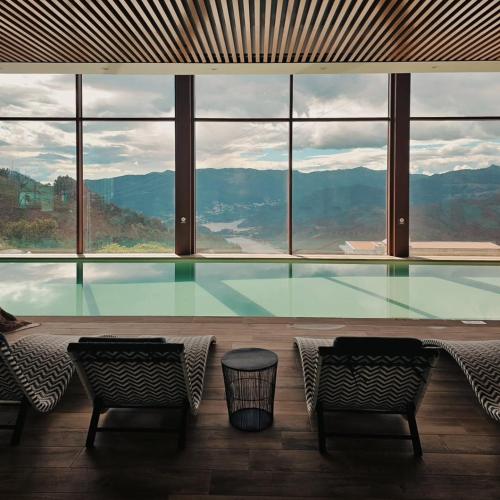 a swimming pool with two chairs and a large window at Encosta de Louredo by Pousadela Village in Vieira do Minho