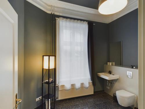 a bathroom with a toilet and a sink and a window at Art Apartments in Hamburg
